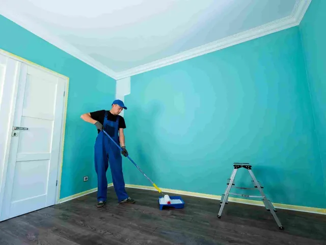 Painter on a ladder applying exterior paint to an Auckland weatherboard home
