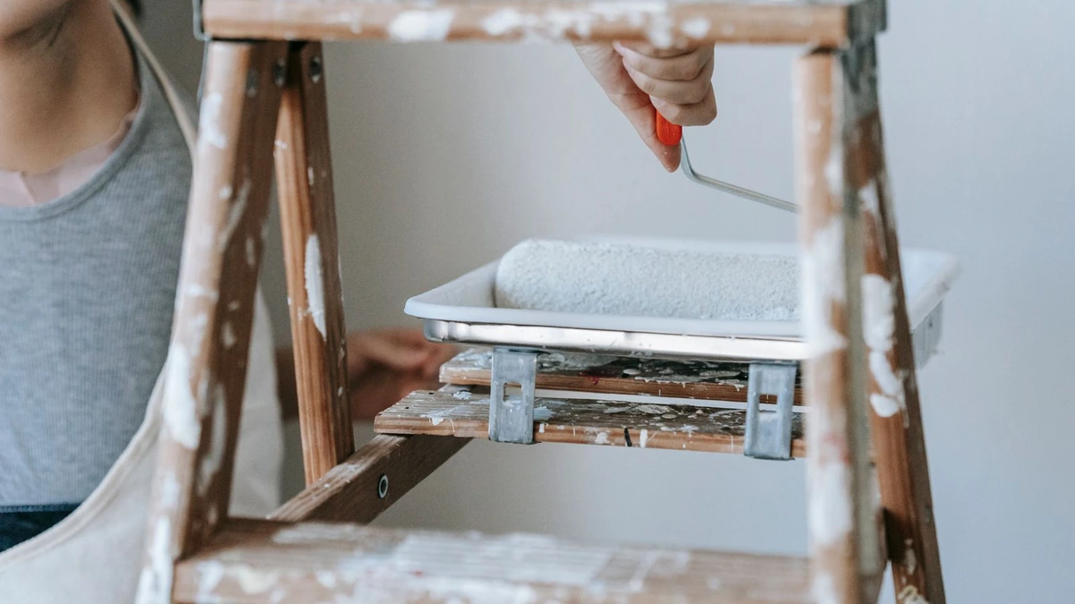 Painter stepladder holding a paint tray and roller during interior painting, the work behind interior painting cost