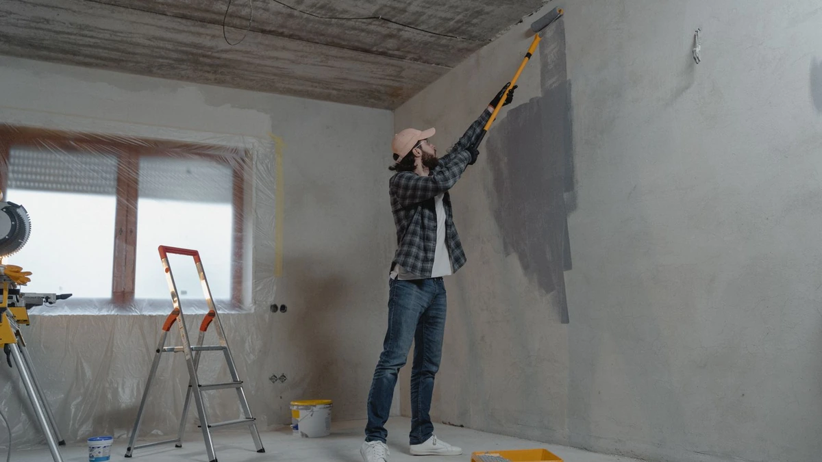Painter rolling a wall in an empty room, the repaint done when painting a rental property between tenancies