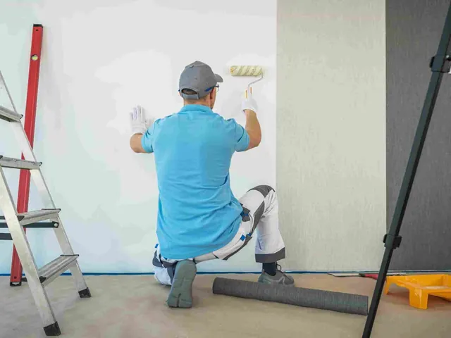 Painter preparing timber weatherboard cladding before repainting an Auckland home