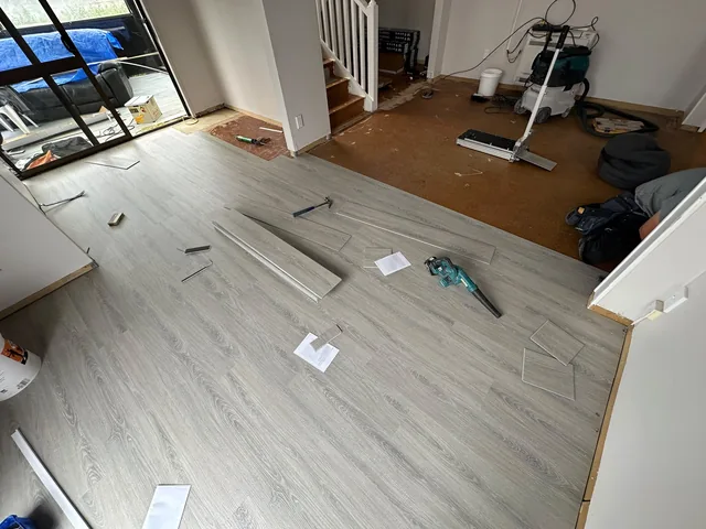 Click-lock laminate planks being laid over a prepared subfloor in an Auckland home