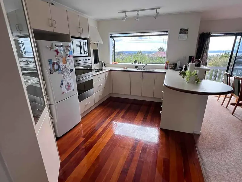 Renovated kitchen with polished timber flooring and harbour outlook in an Auckland home by My Homes Construct Ltd